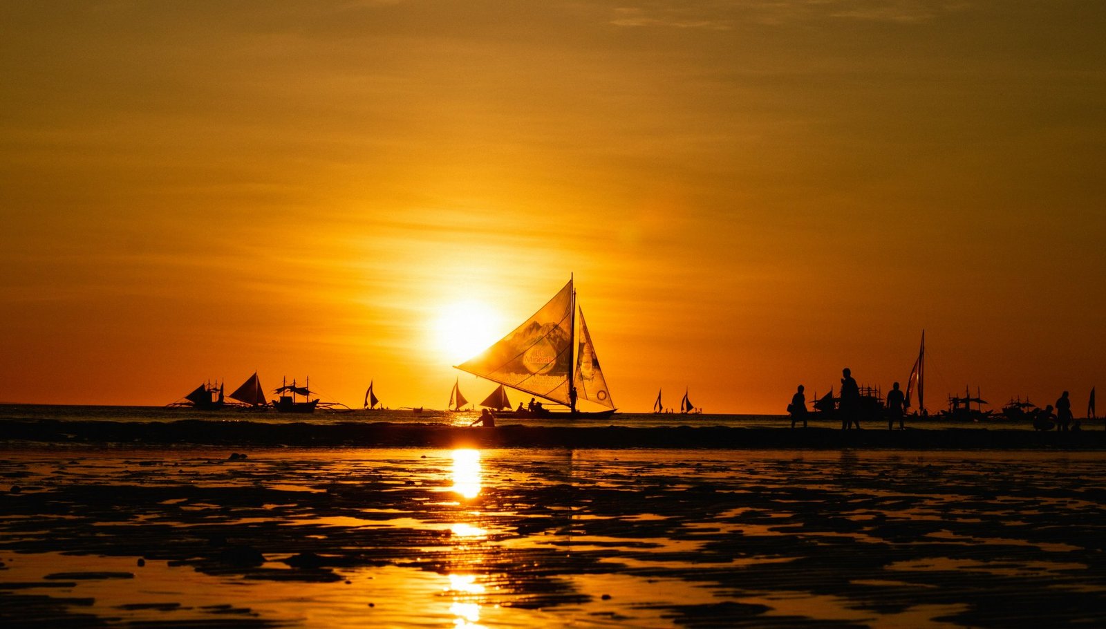 A sailboat silhouetted against the setting sun