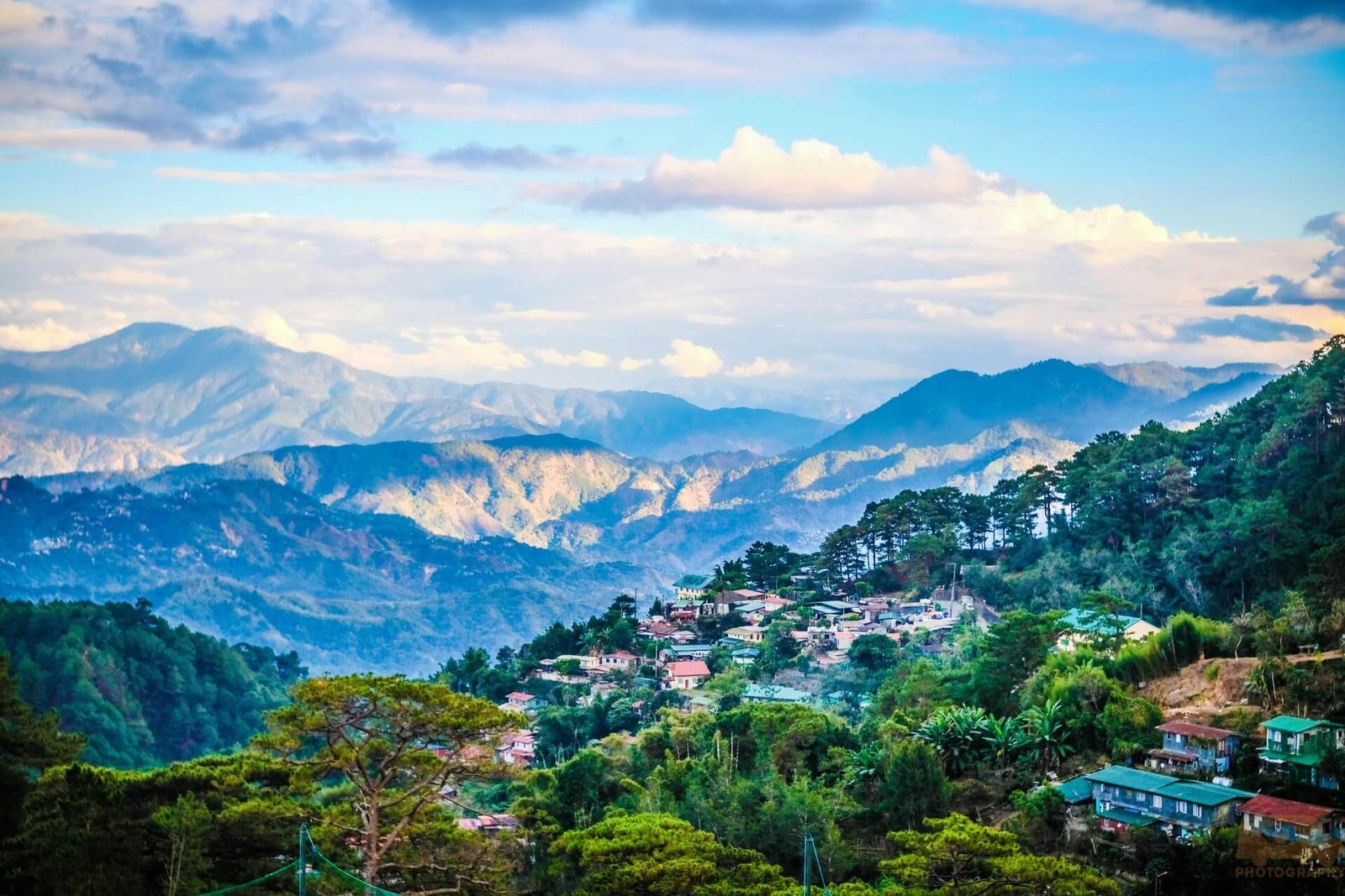 Houses on green hills in Baguio with layers of mountains behind