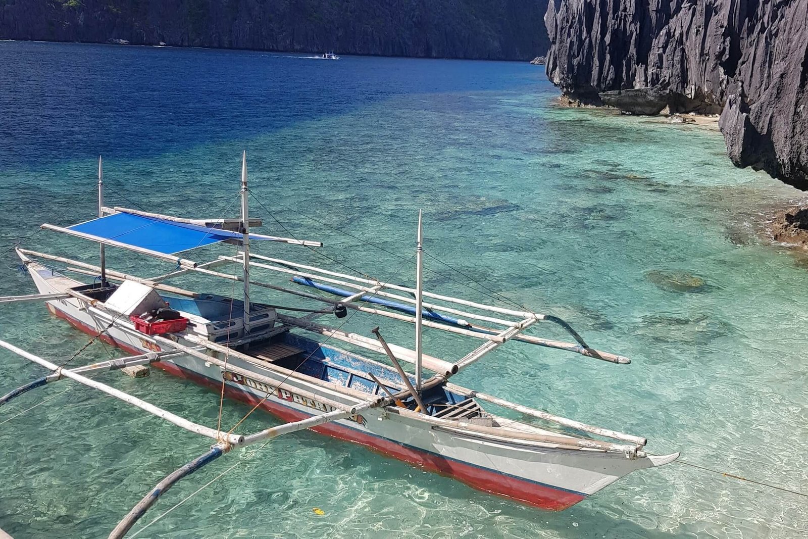 Traditional bangka outrigger boat anchored in clear water on an El Nido island hopping tour