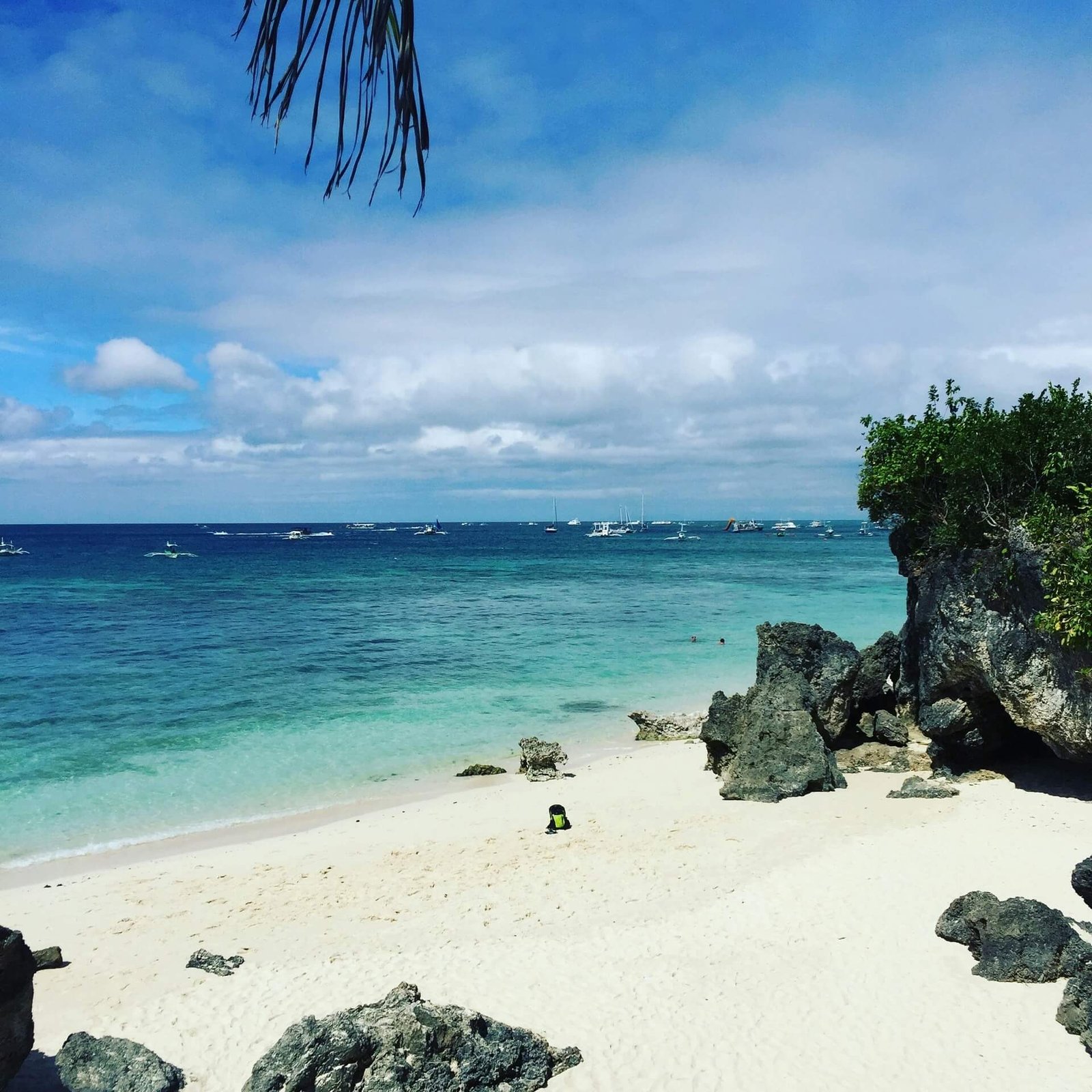 Small white-sand cove with dark rocks and turquoise water in Boracay