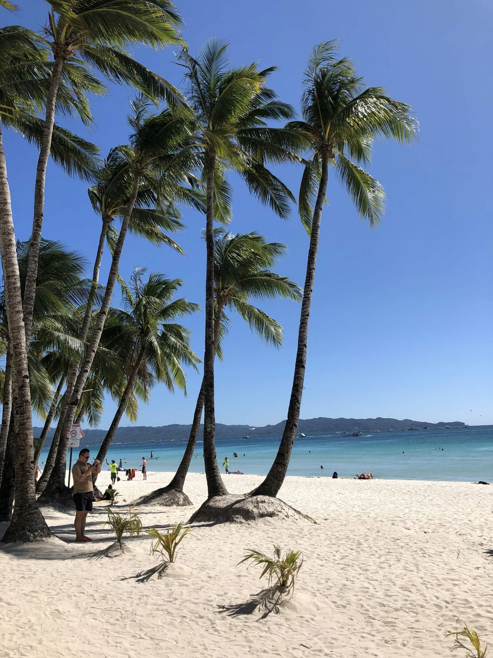 Palm trees and people on the powdery sand of White Beach, Boracay