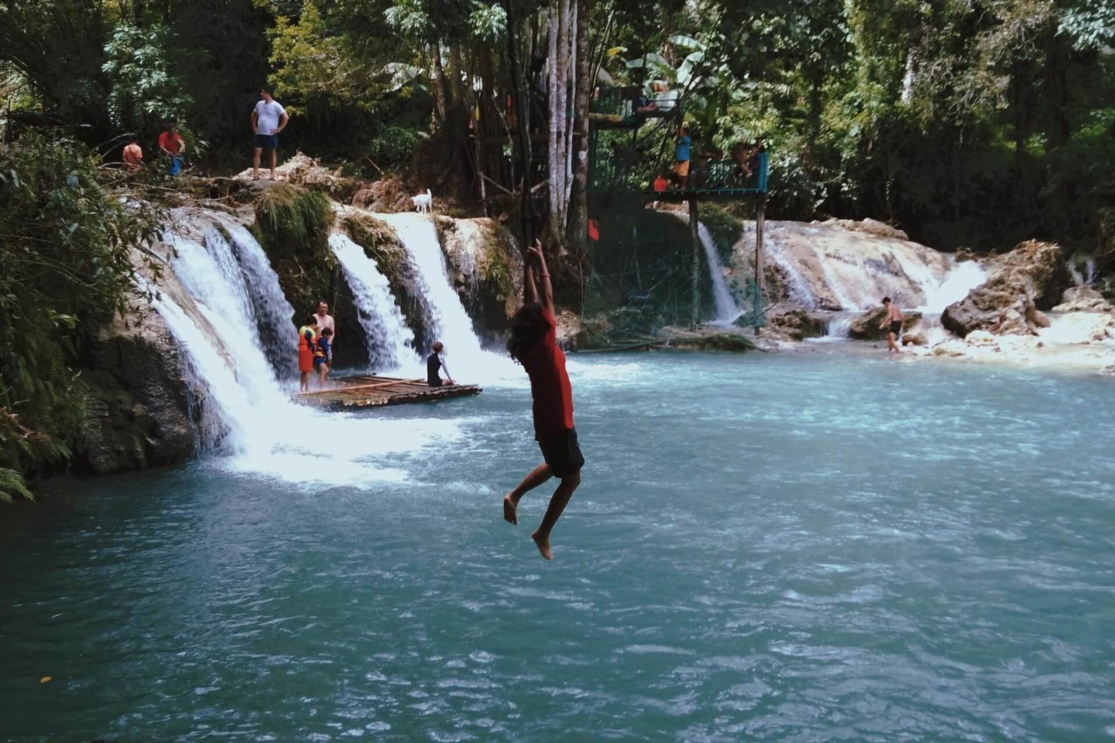 Visitor jumping from the rope swing into the pool at Cambugahay Falls, Siquijor