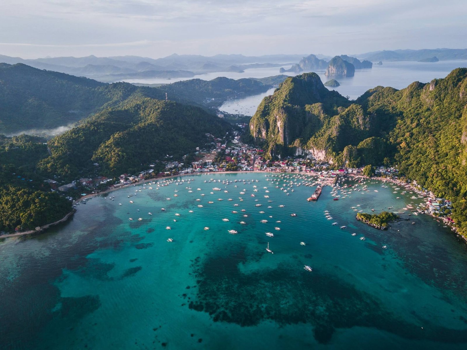 Aerial view of El Nido town and boats in Bacuit Bay below limestone cliffs, Palawan