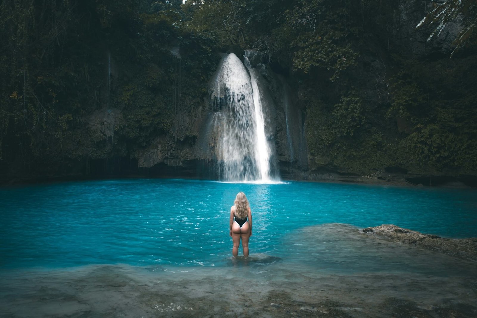 Swimmer in the turquoise pool below Kawasan Falls at sunrise, Badian, Cebu