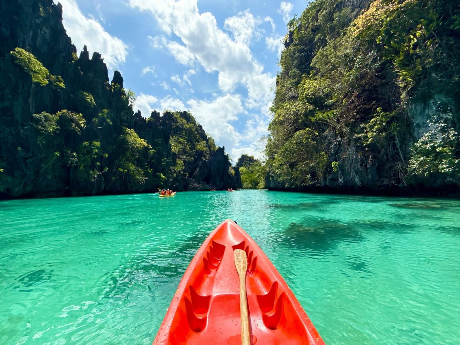 Kayak gliding through turquoise water between limestone cliffs in El Nido, Palawan