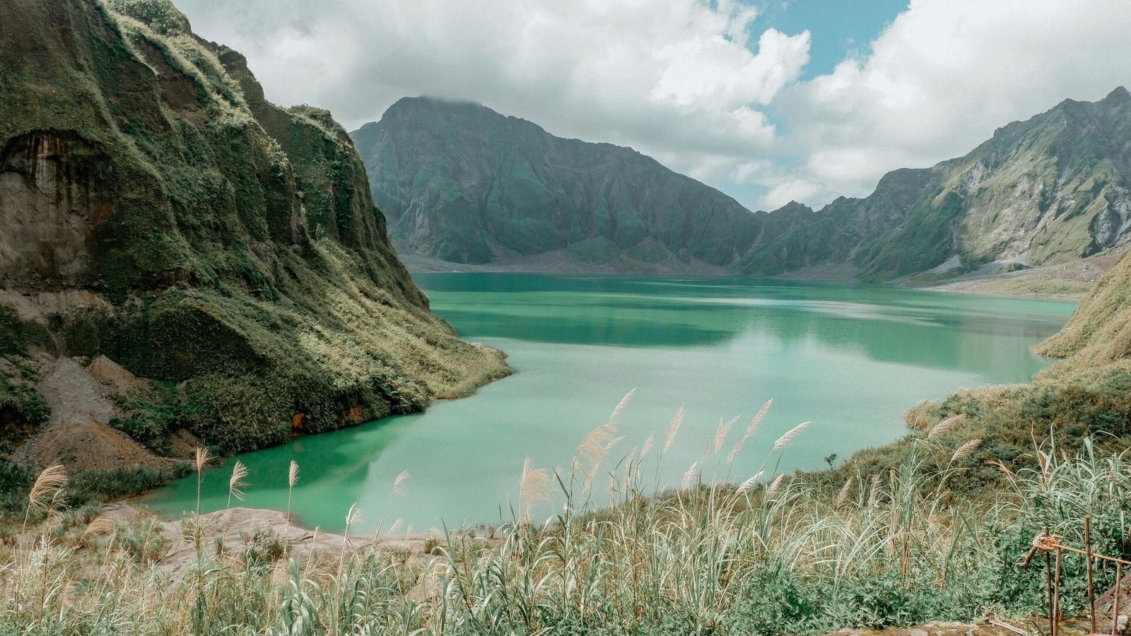 Turquoise Mt Pinatubo crater lake below grassy cliffs in Botolan, Zambales